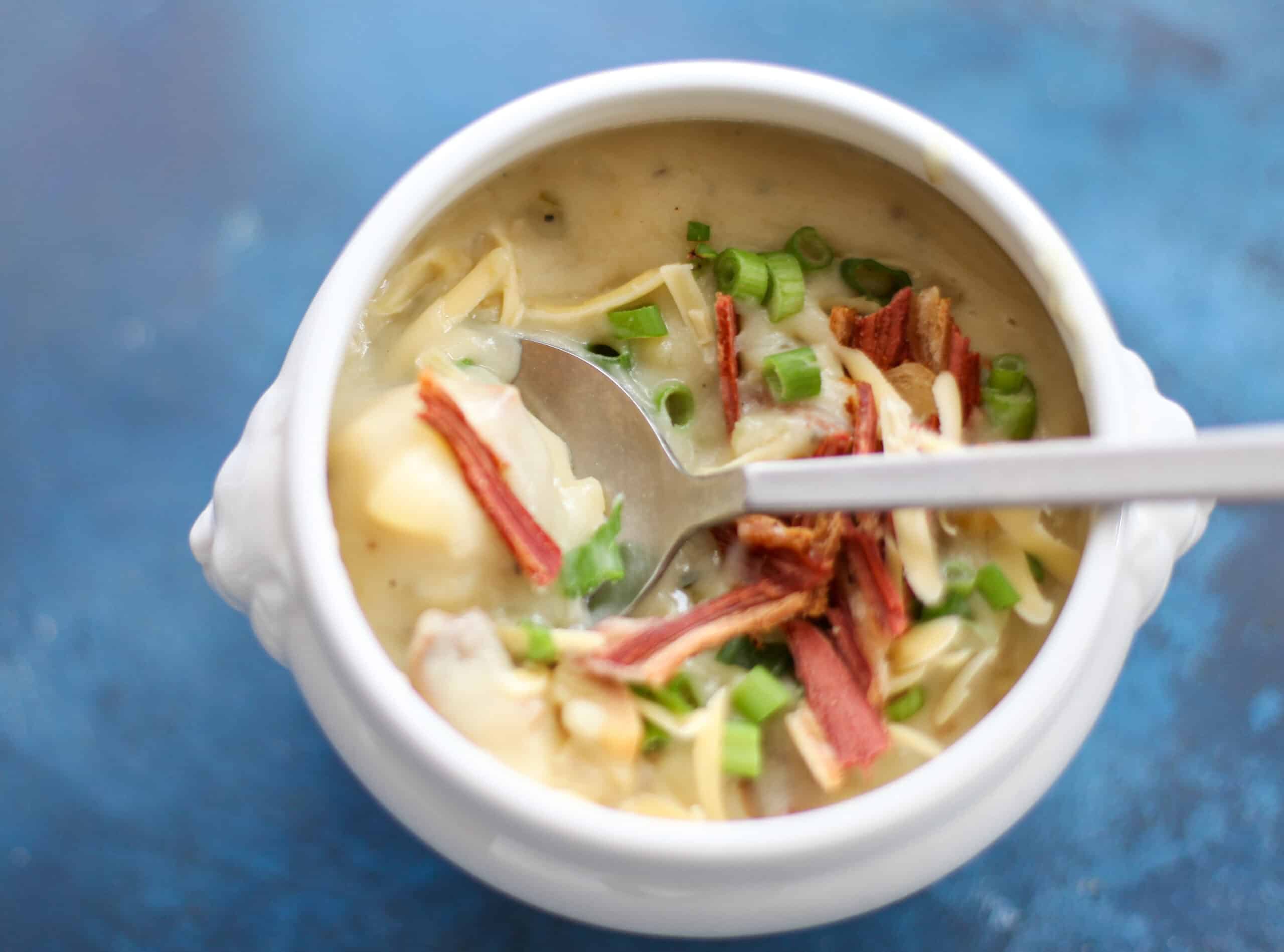 A bowl of baked potato soup with a spoon.