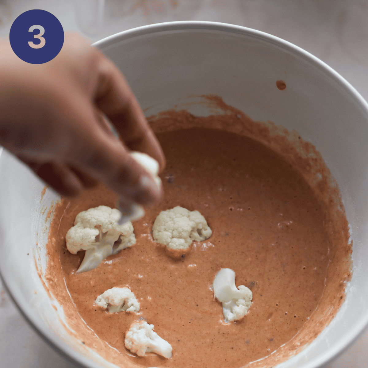 dropping cauliflower florets into batter.