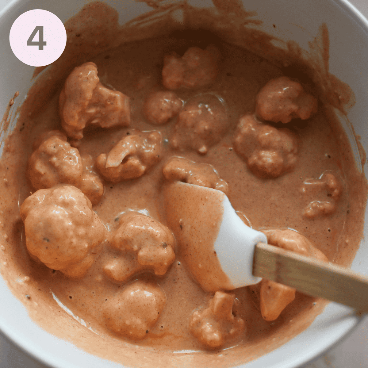 Ensuring cauliflower is fully coated in batter.