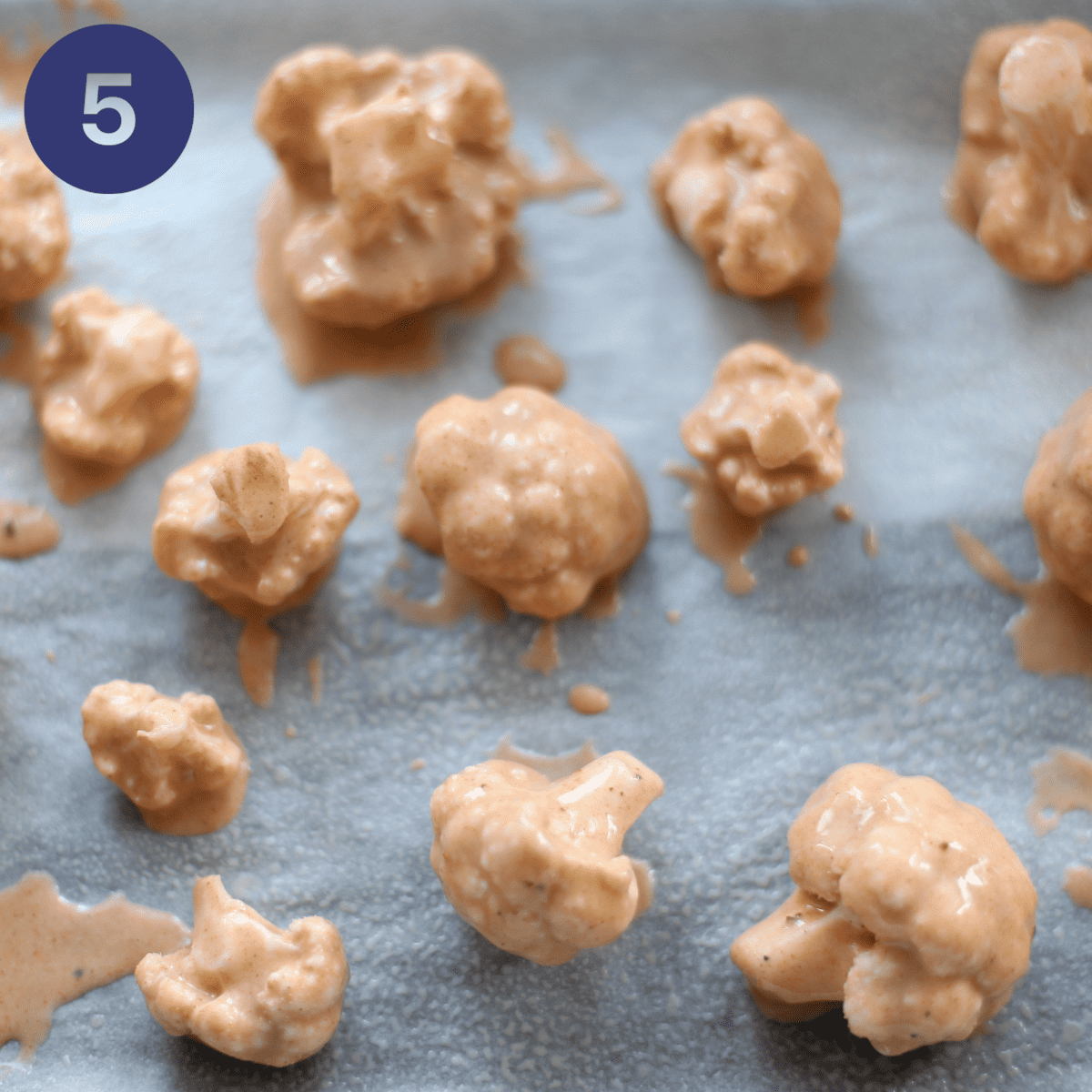 Placing battered cauliflower onto a baking sheet.