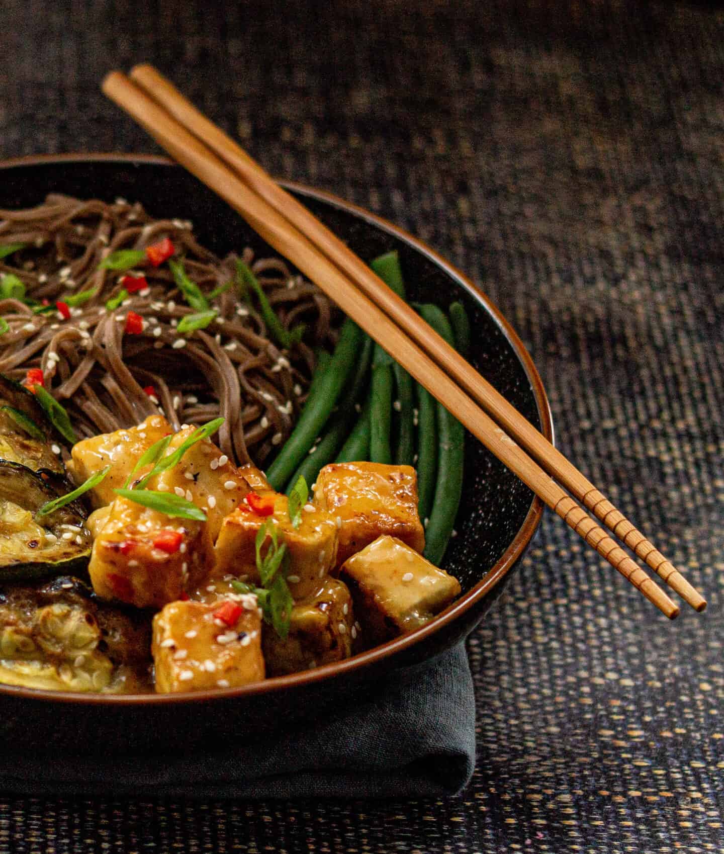 A tofu bowl with noodles and chopsticks