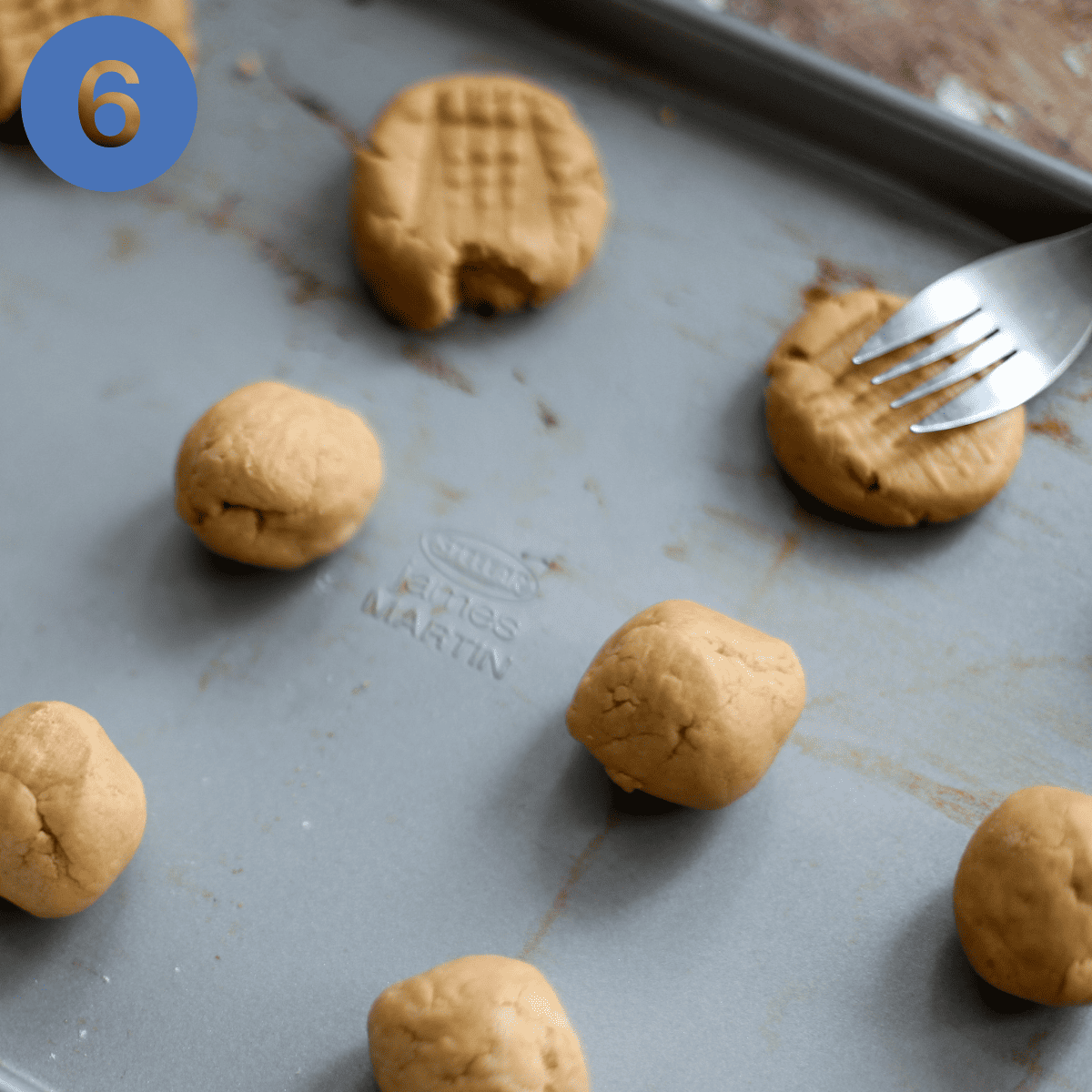 Putting a criss-cross pattern onto peanut butter cookie dough using a fork.