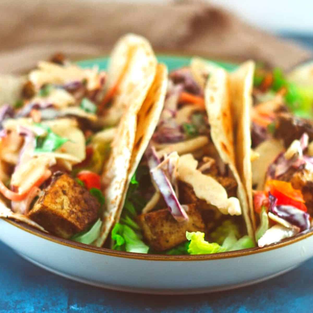 A plate of tofu tacos with salad