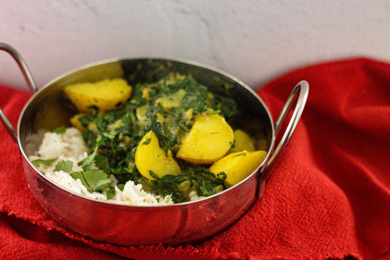 A dish with sag aloo and rice.