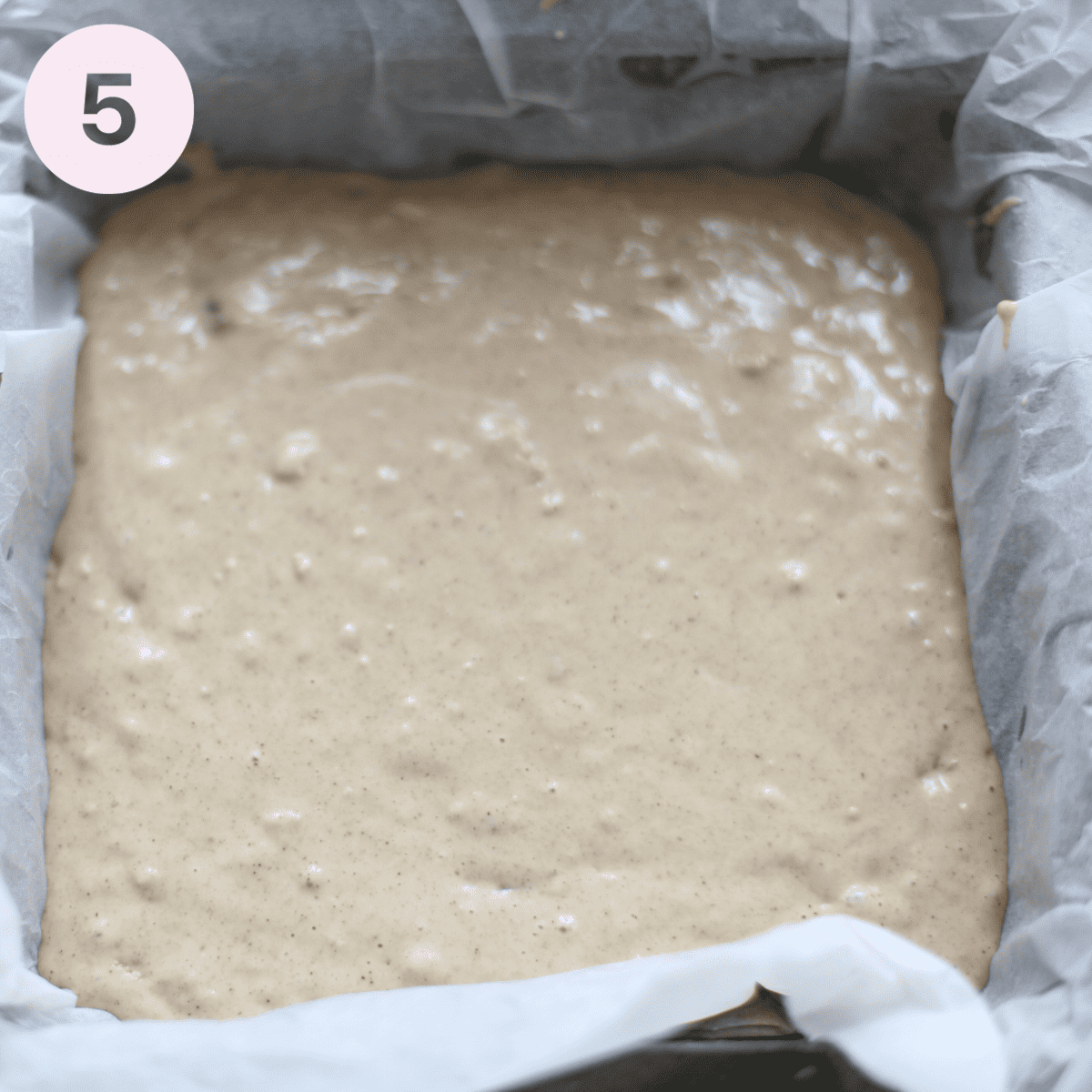 Pouring cake batter into a lined cake tin.