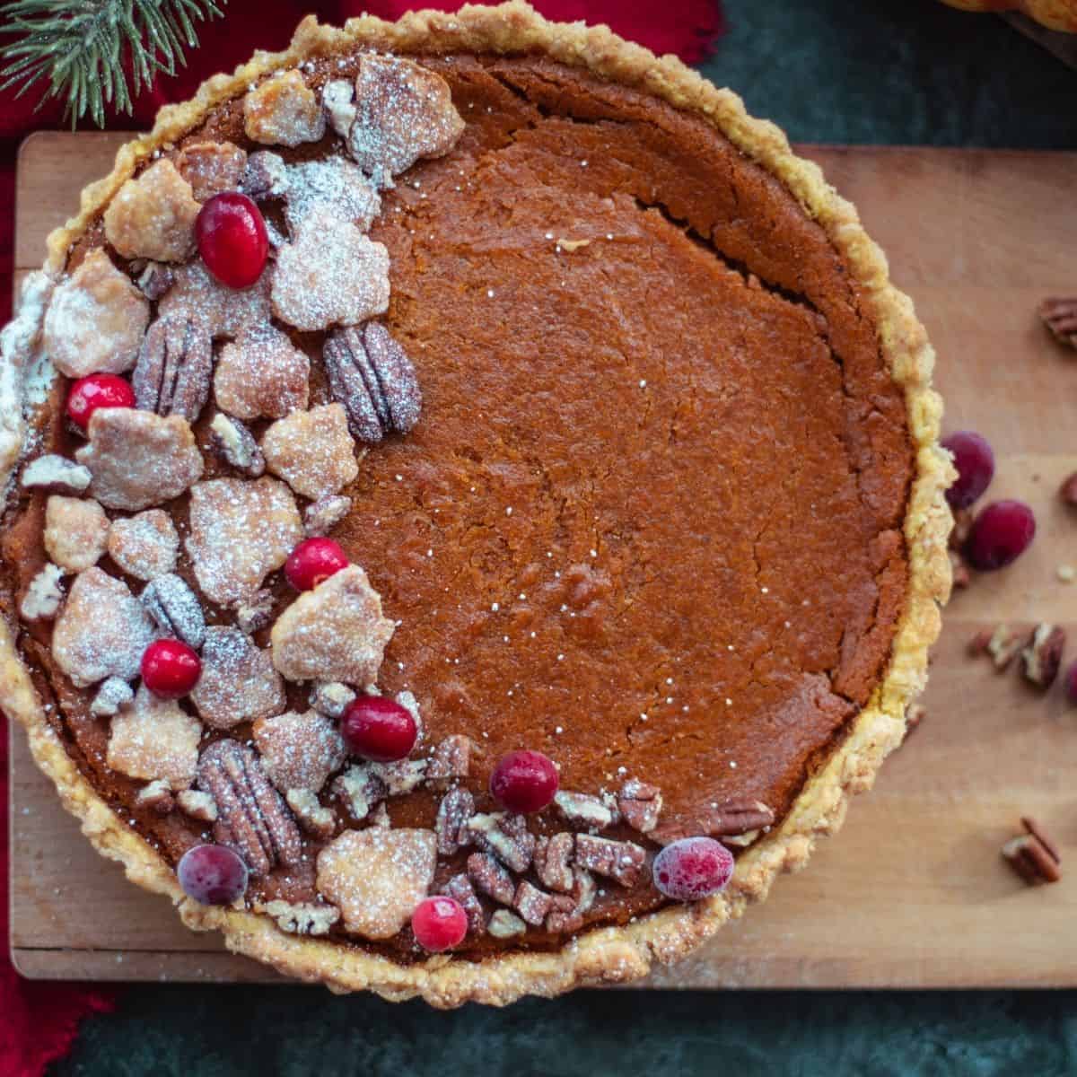 A vegan pumpkin pie decorated with cranberries and pecans