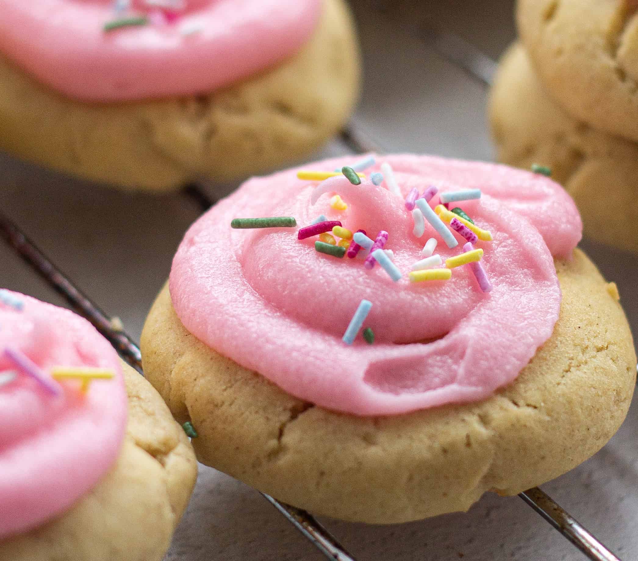 A close up of a pink cookie with sprinkles