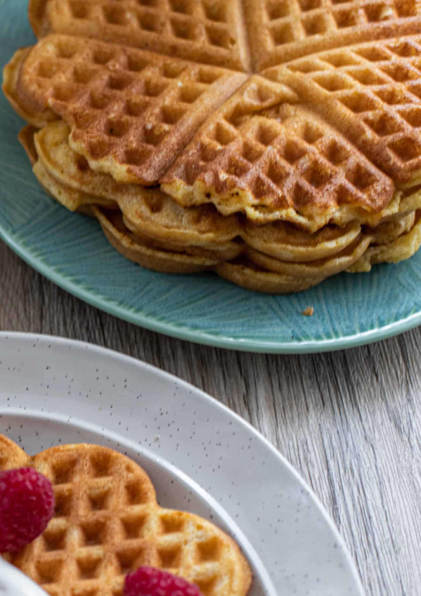 A stack of cornmeal waffles with raspberries