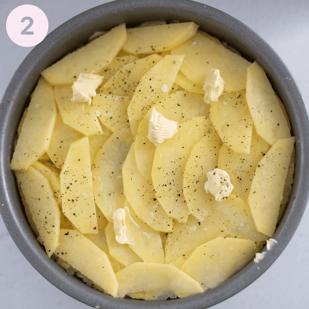 Layering up sliced potatoes.