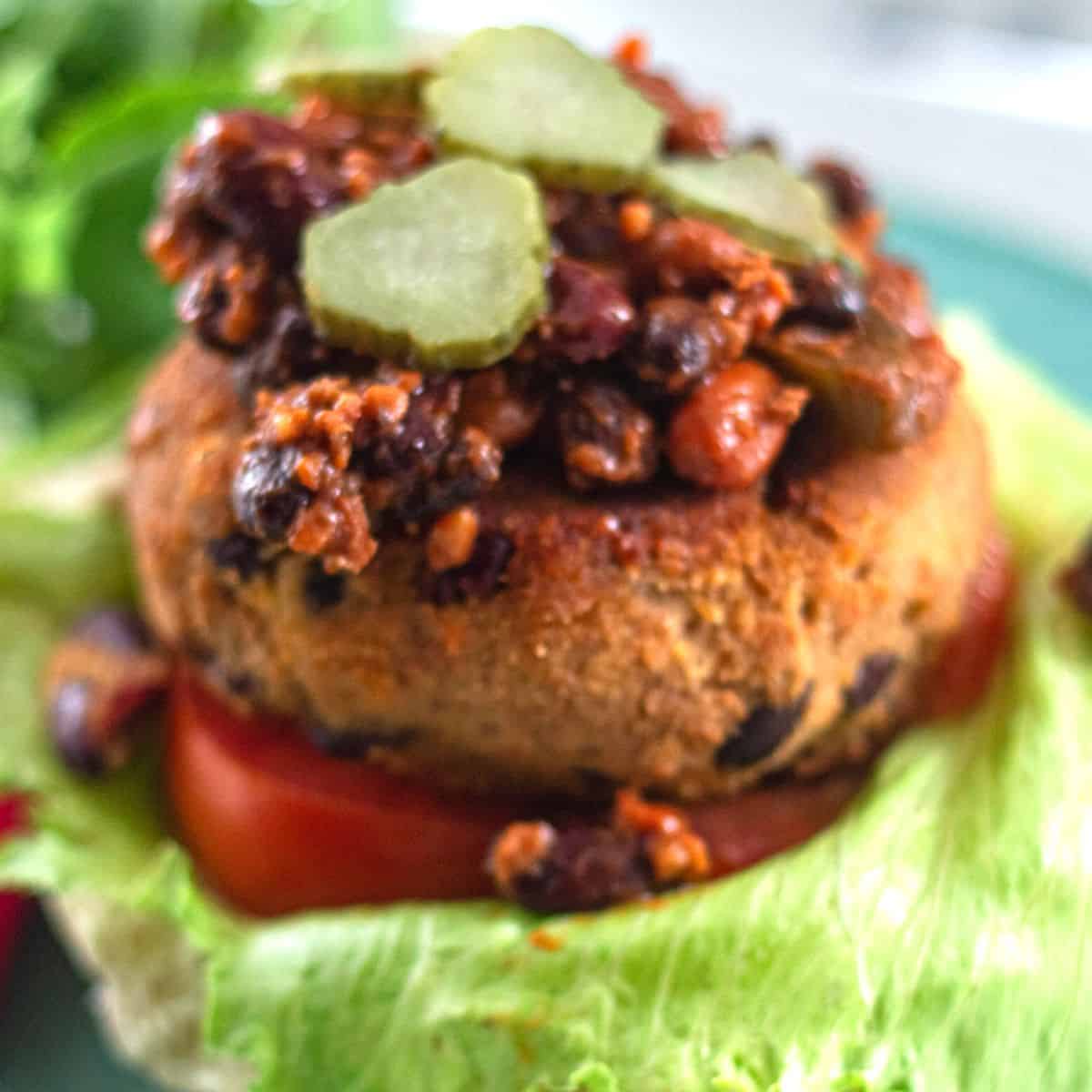 Spicy Bean Burger on a plate with pickles and lettuce