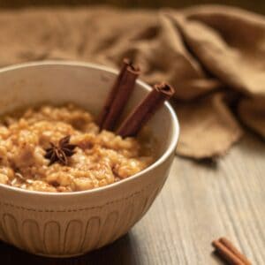 A bowl of rice pudding with cinnamon sticks