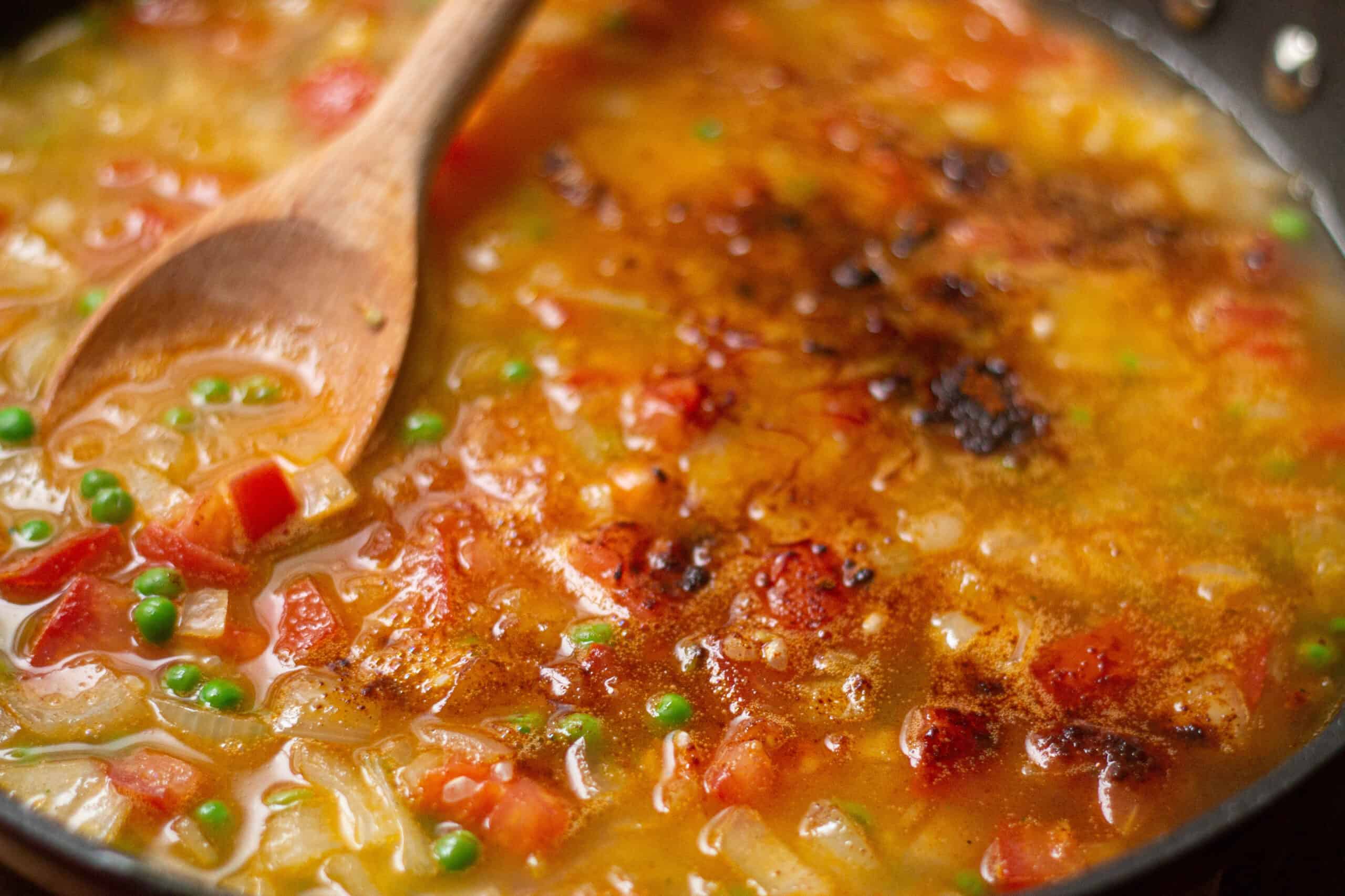 adding the stock and spices to the paelle