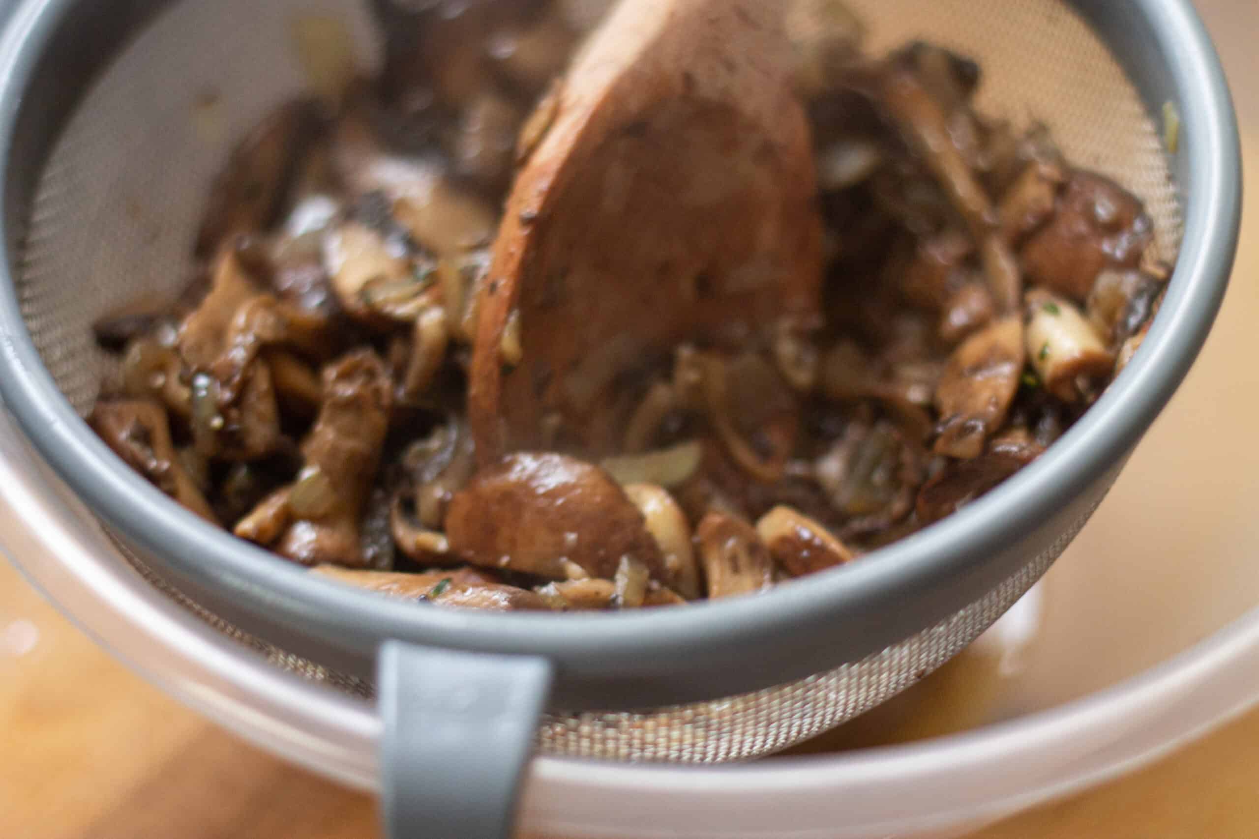 Mushroom soup being pressed through a sieve