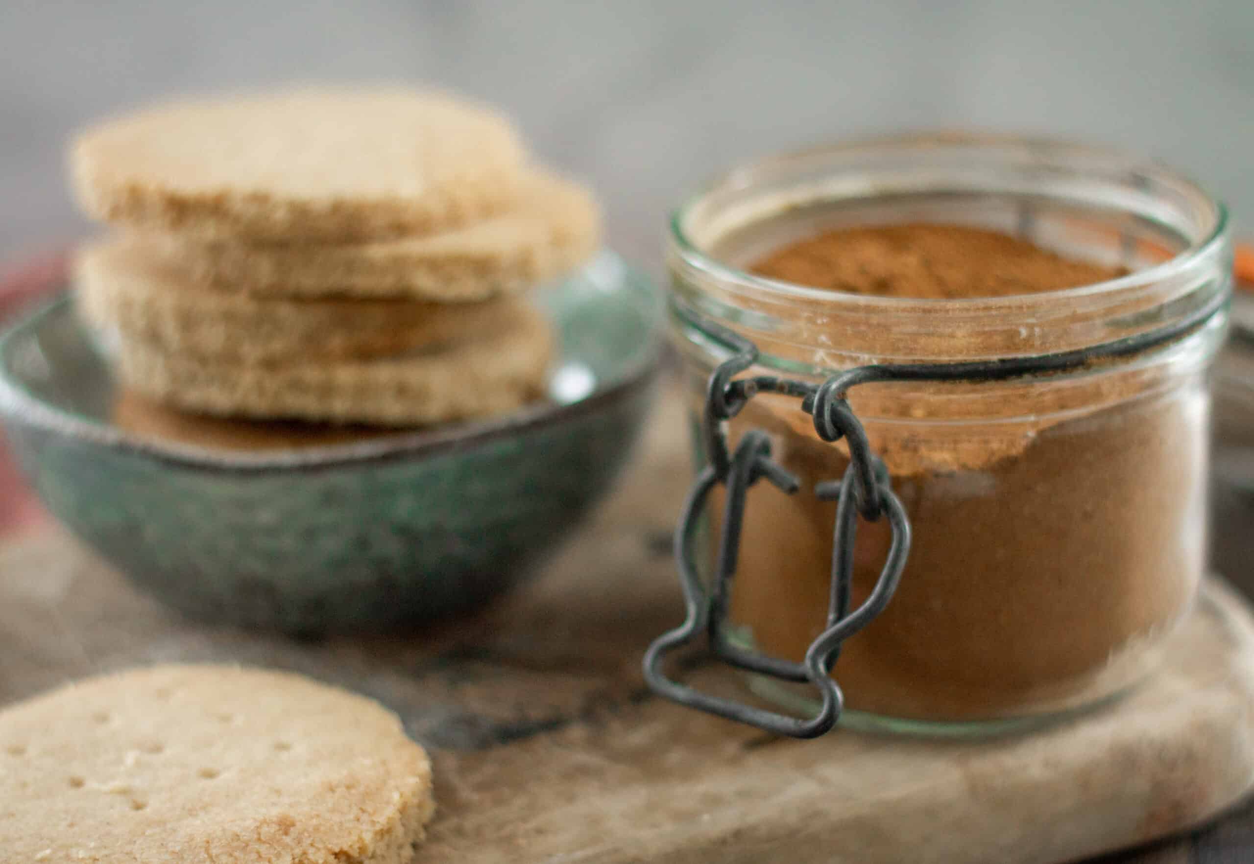 A jar of chai powder next to a stack of shortbread cookies
