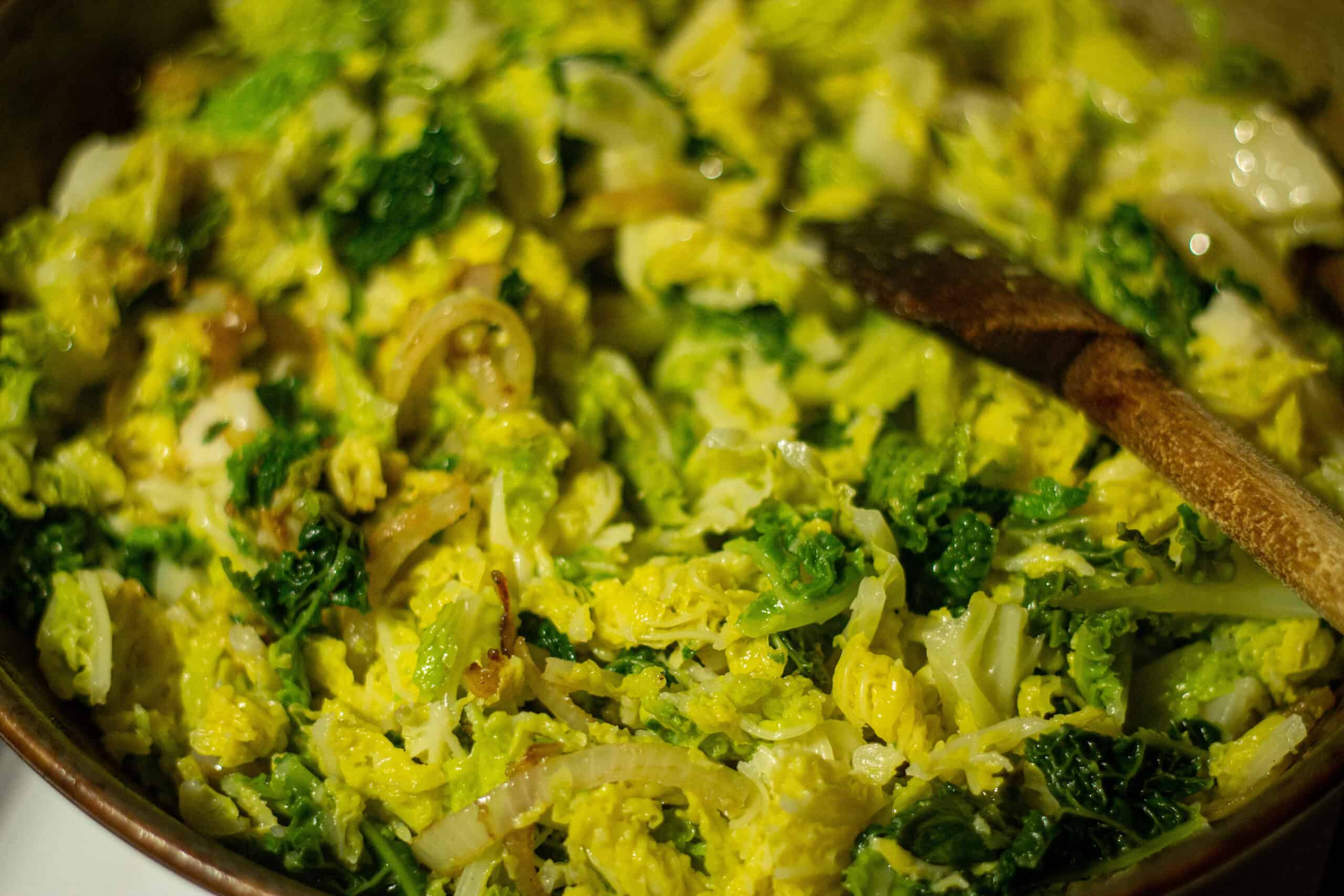 Cabbage being stirred into fried onions