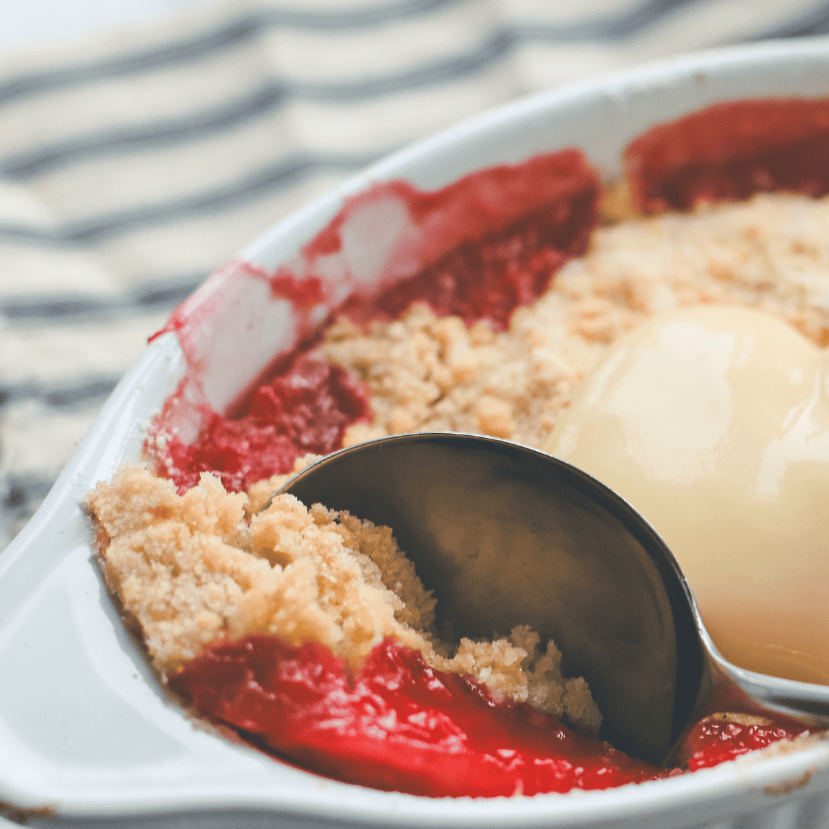 A fruit crumble with a spoonful taken out.