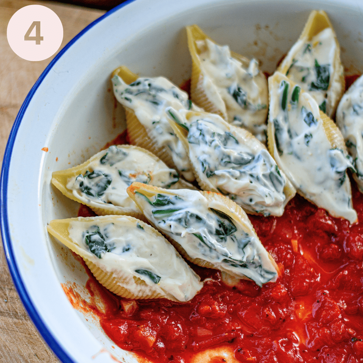 Layering up the pasta shells in a baking dish.
