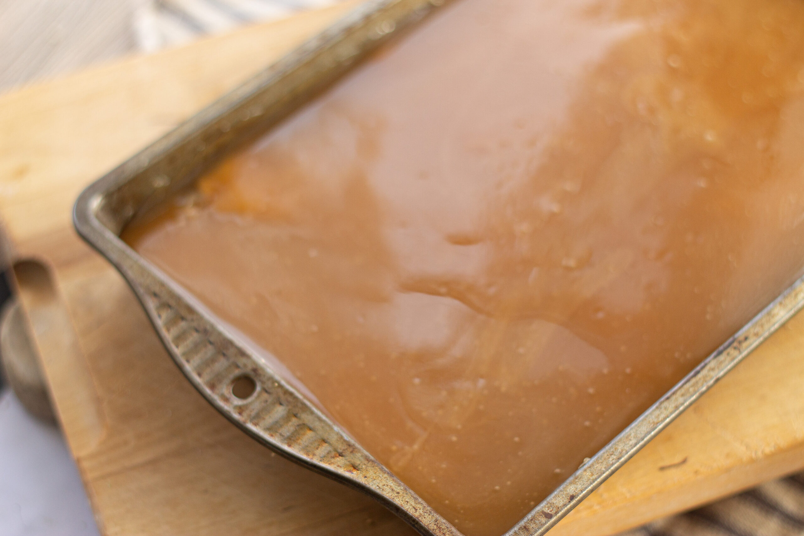 Pouring caramel over baked shortbread