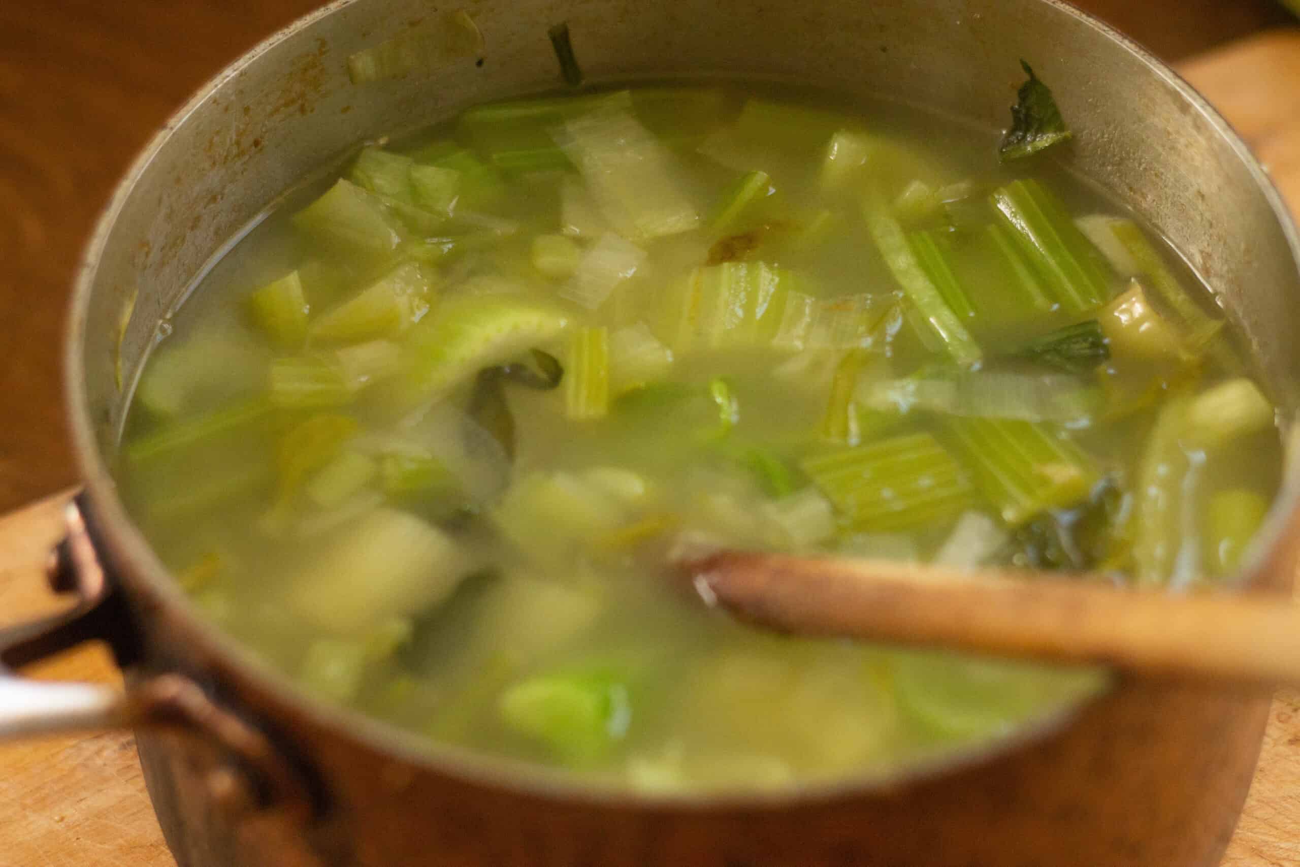 Once tender, adding stock to vegetables