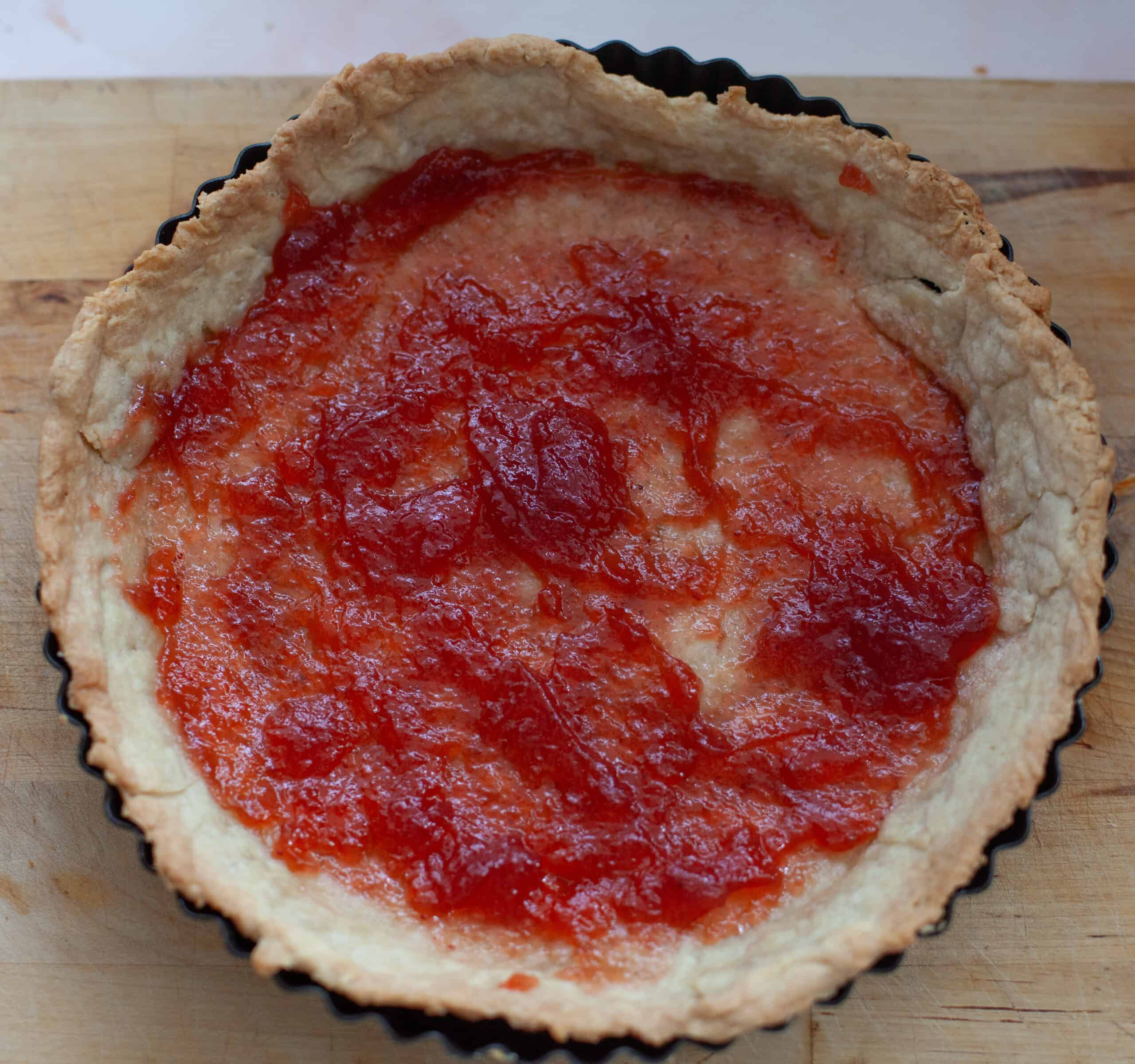 Jam spread on the bottom of baked pie case.