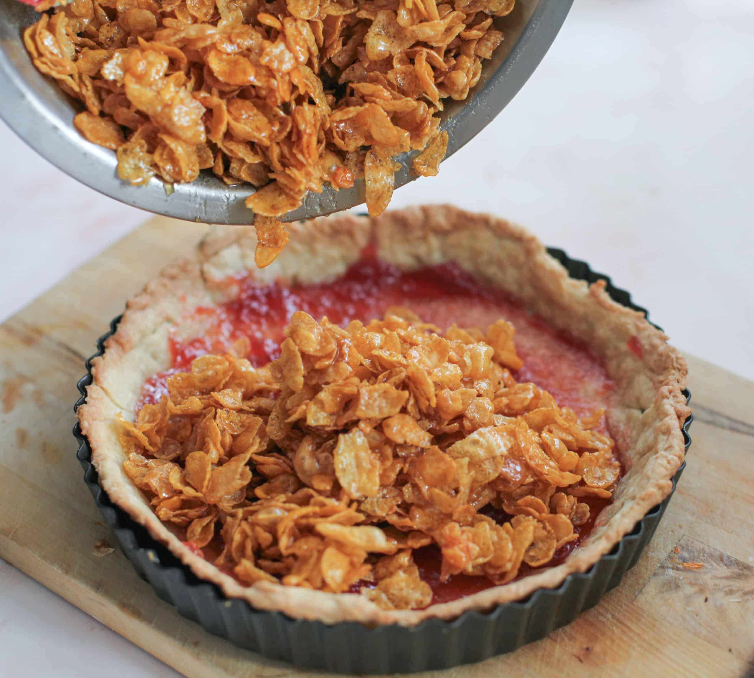 Spooning combined cornflake mixture into the pie crust.