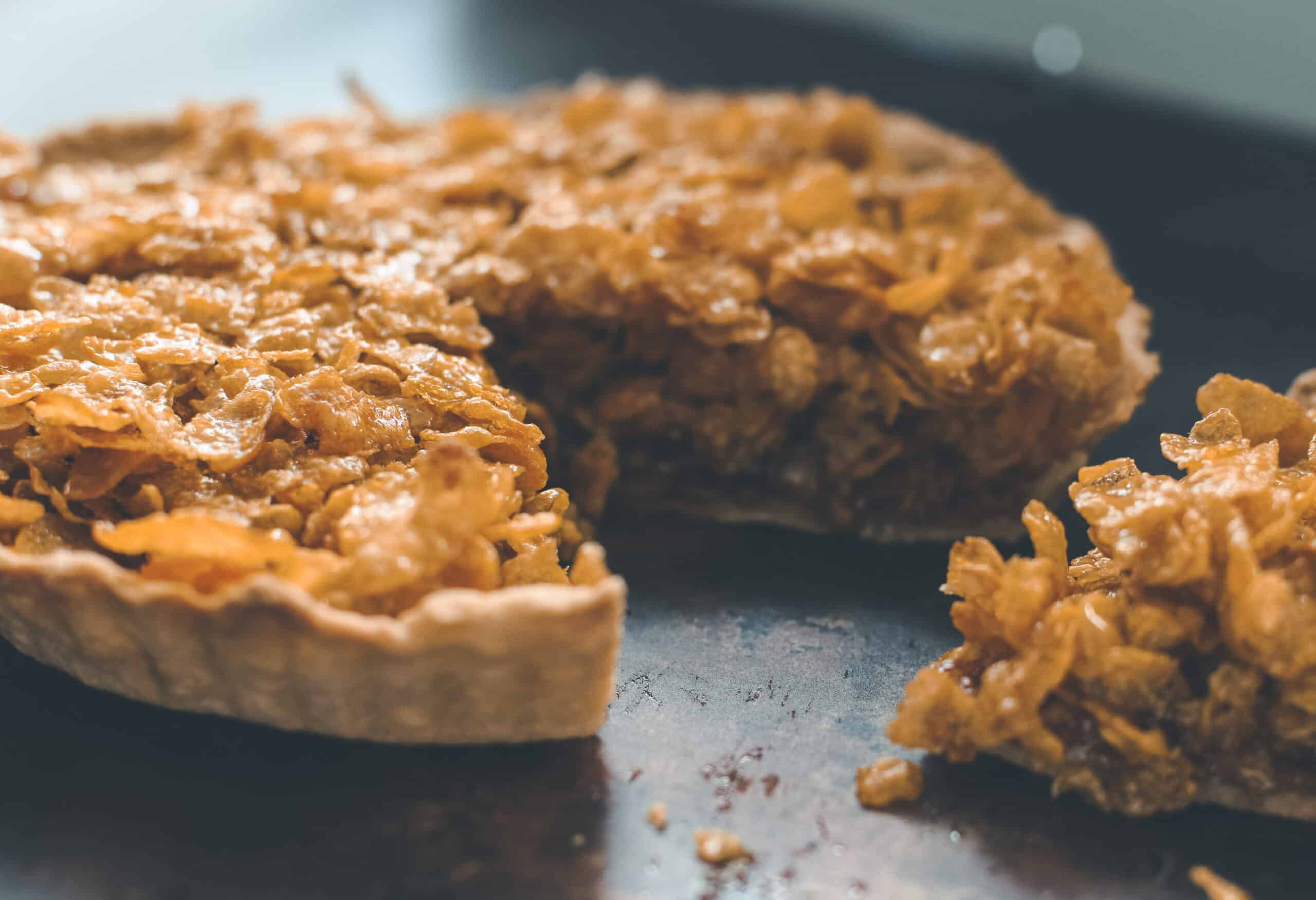 A cornflake tart with a slice cut out.