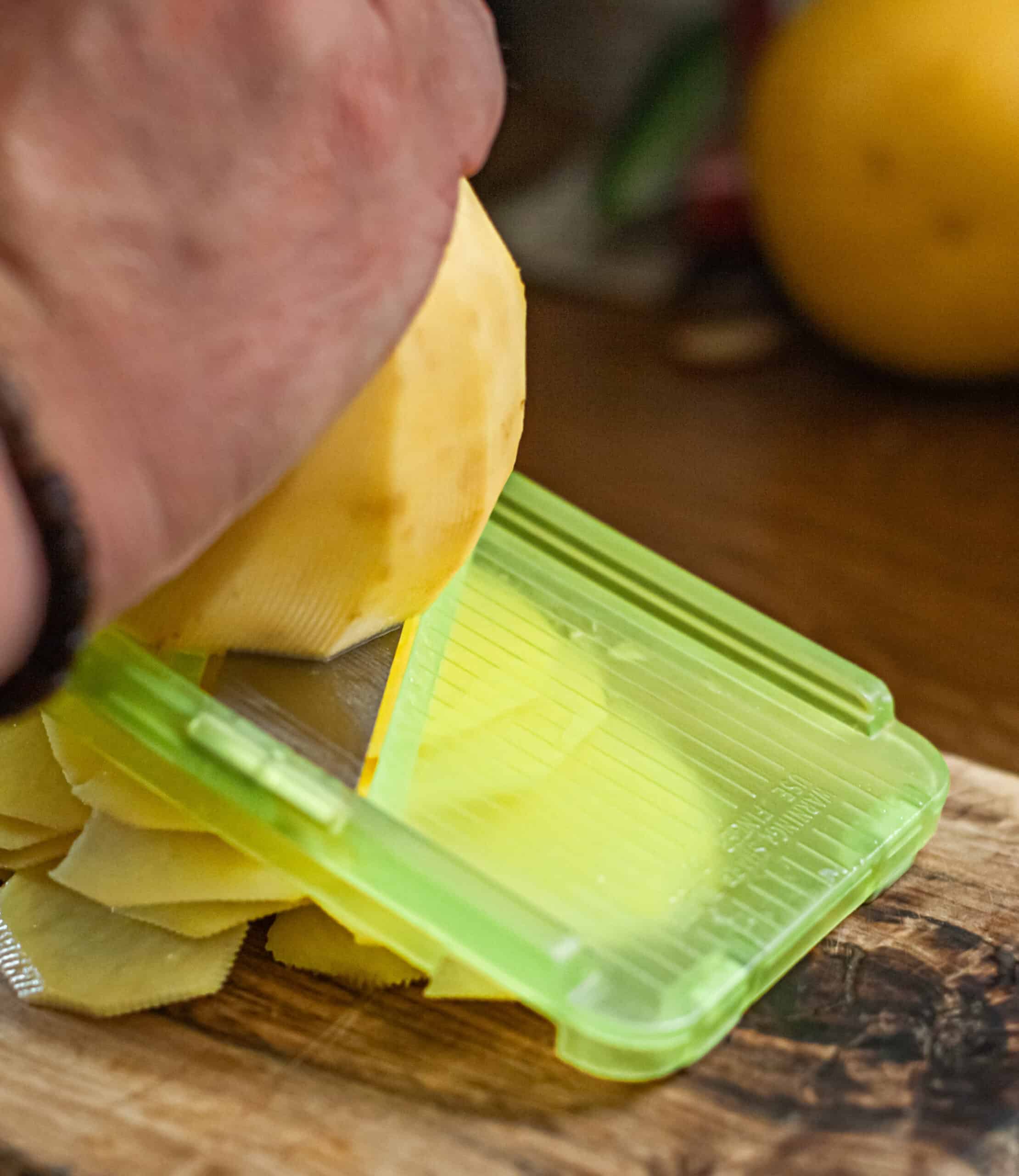 Slicing peeled potatoes using a mandoline.