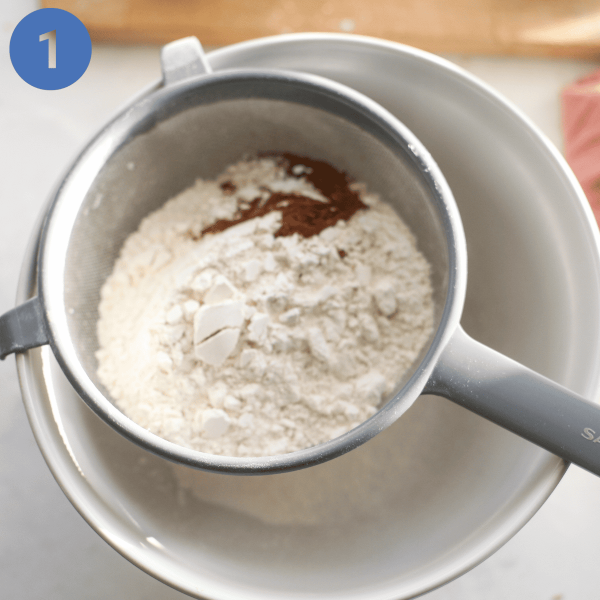 Sifting flour and spice into a mixing bowl.
