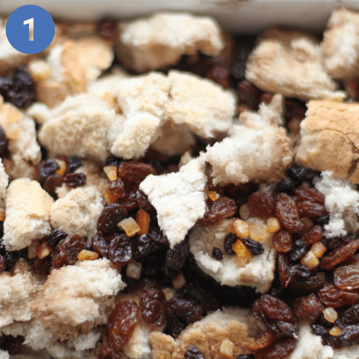 Torn bread and dried fruit in a baking dish.