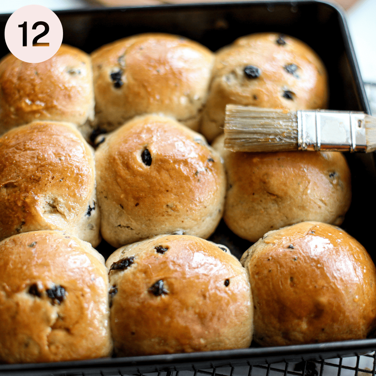 Brushing baked buns with apricot jam.