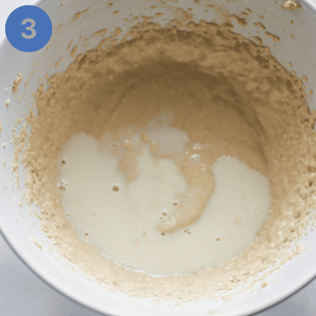 Adding milk to cake batter.