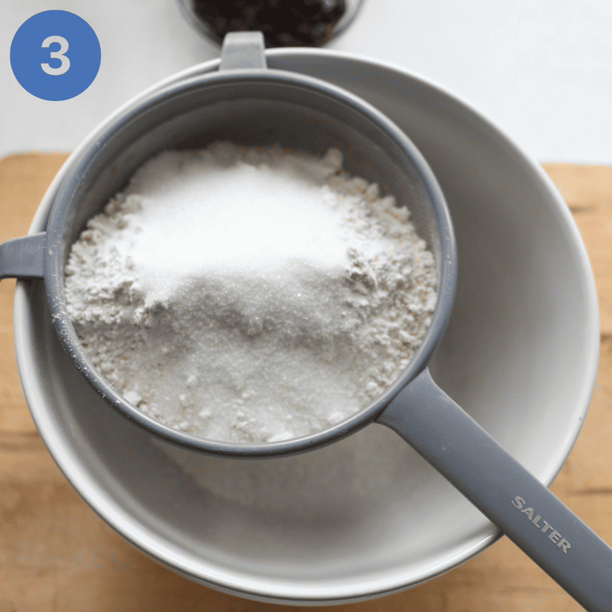 Sifting flour into a mixing bowl.