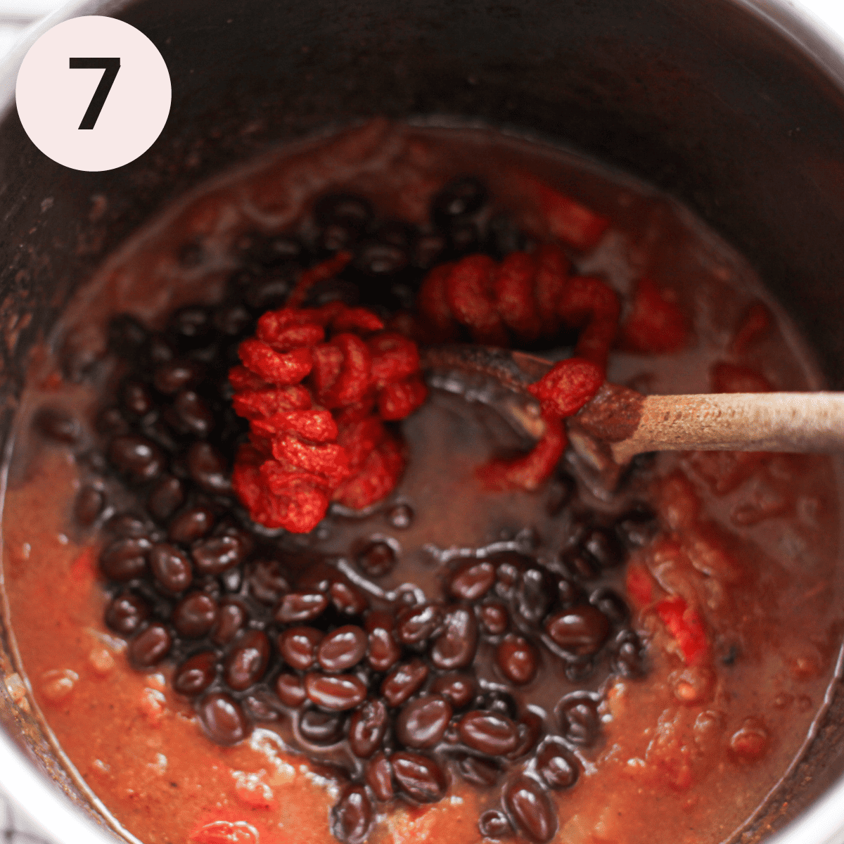 Adding black beans to chili.