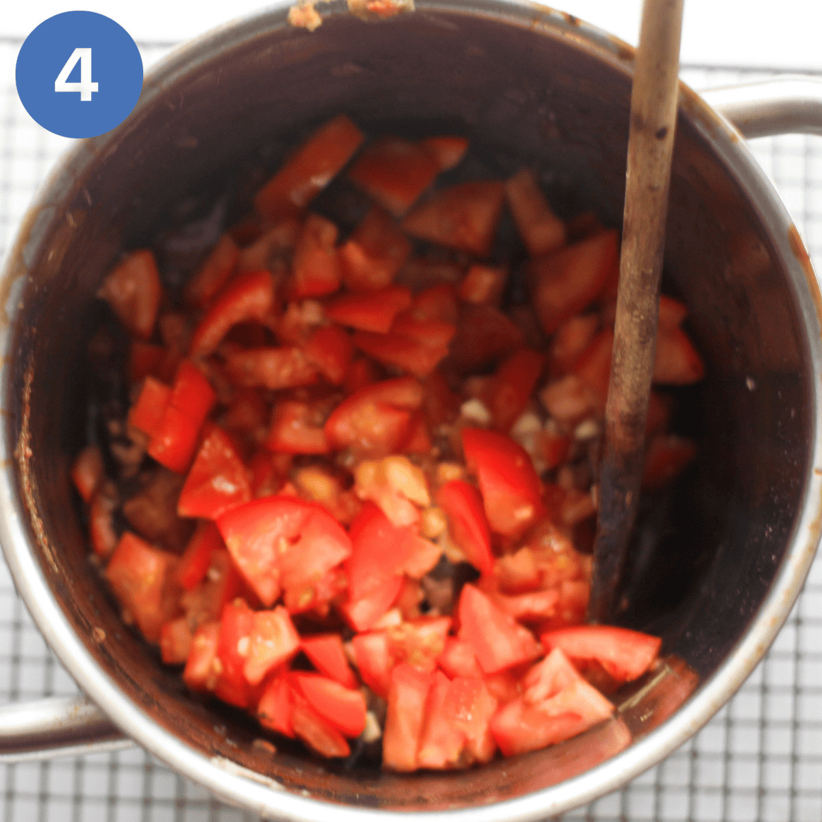 Adding tomatoes to creole.