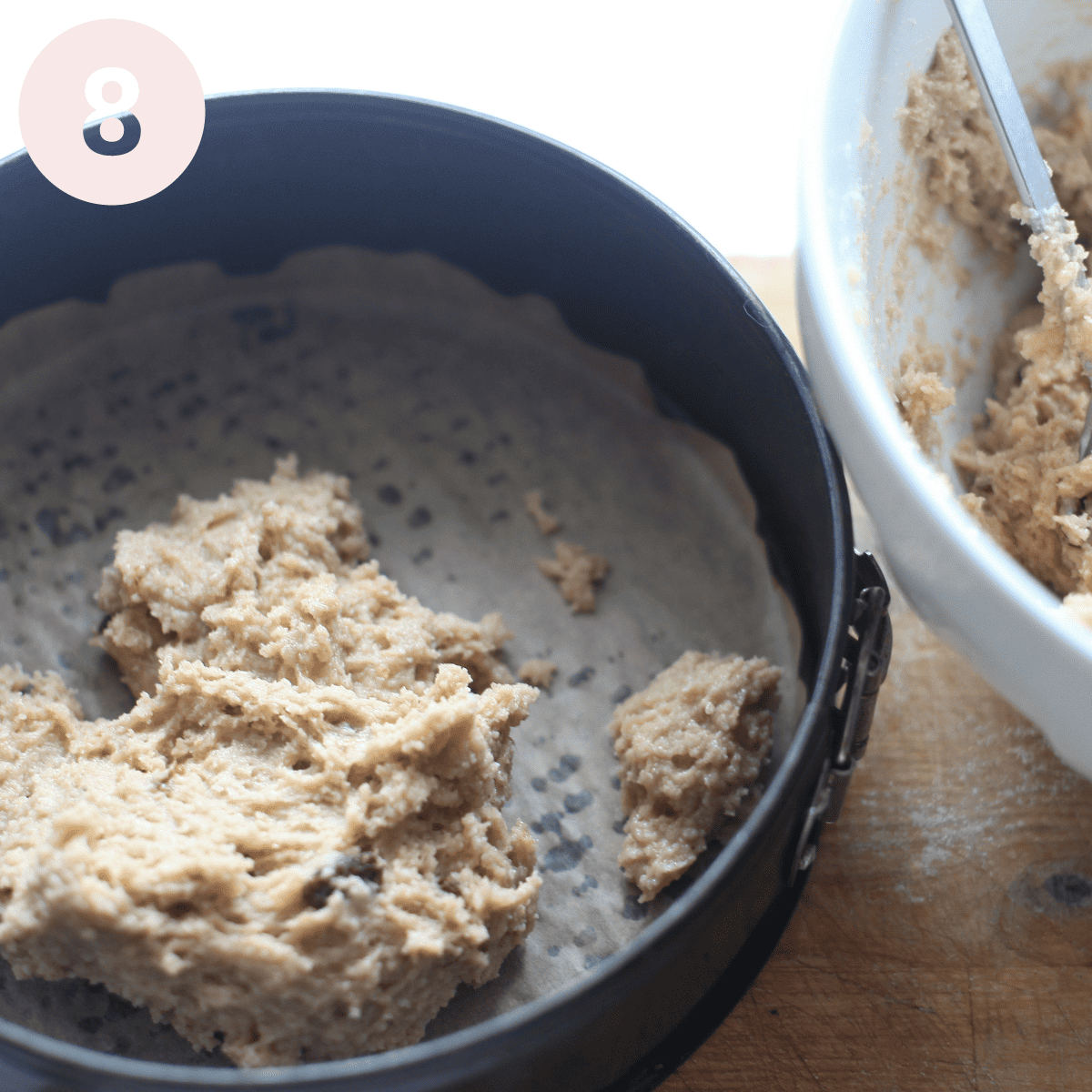 Spooning cake batter into prepared tin.