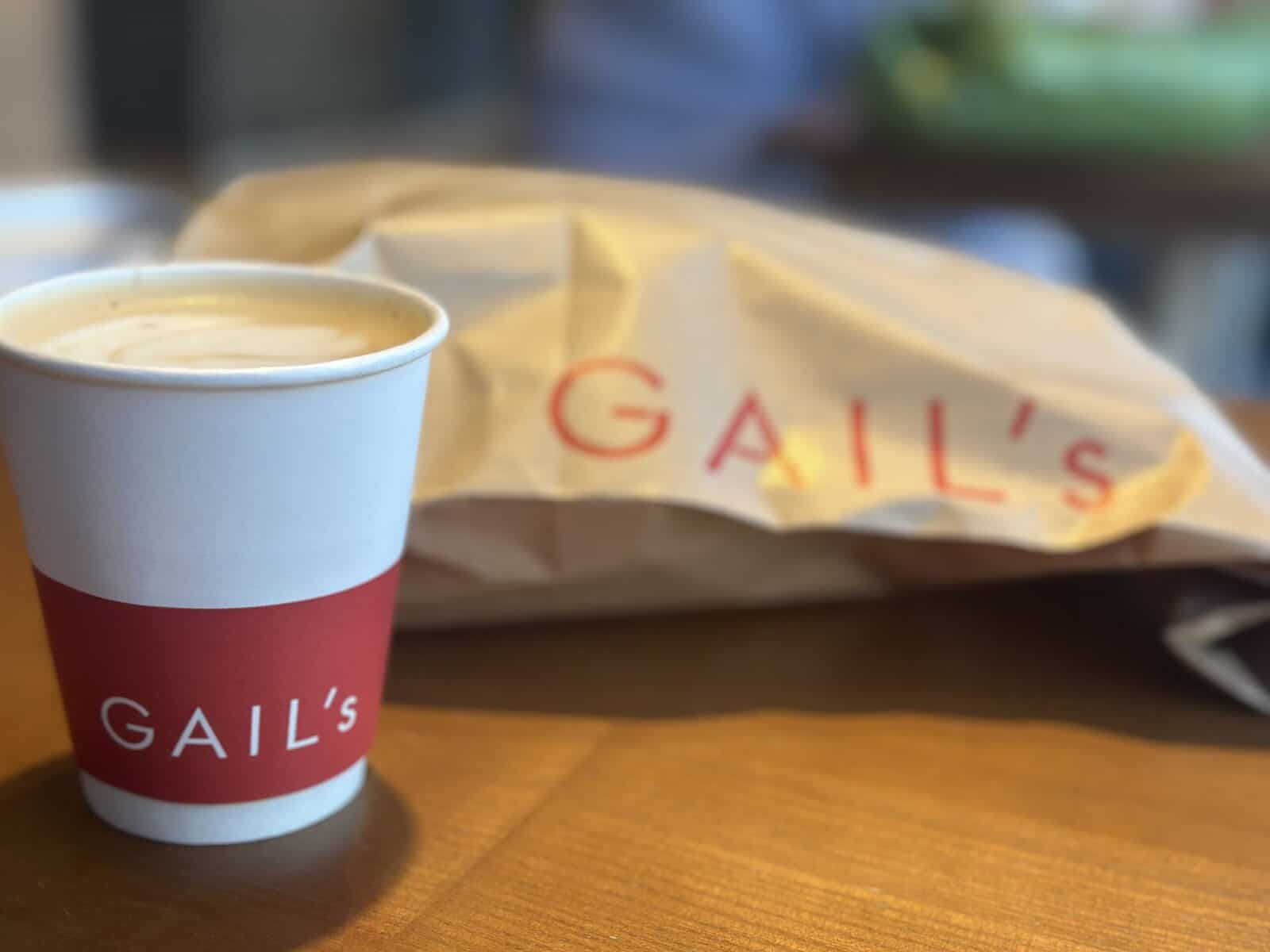 A takeaway cup of coffee with a loaf of dourdough.
